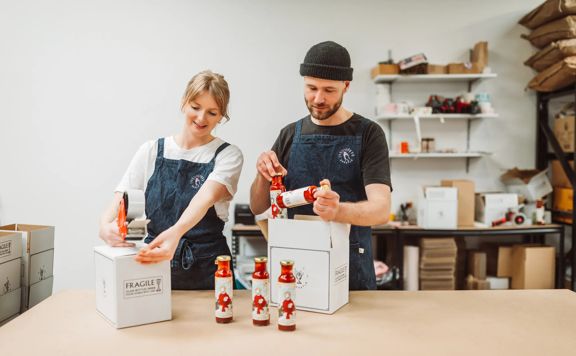 Lydia Harfield and Mat Watkins, co-founders of Apostle Hot Sauce, bottle and package their product from their kitchen.