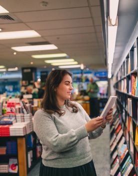 A person reads a book inside Unity books, while standing in front of a colourful bookshelf.