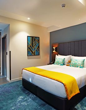 A room inside The Sebel, Lower Hutt. The room has blue carpet and walls with gold accents throughout.