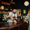 A smiling bartender passes a perfectly poured pint of Guinness to a happy patron at Regent cocktail pub.