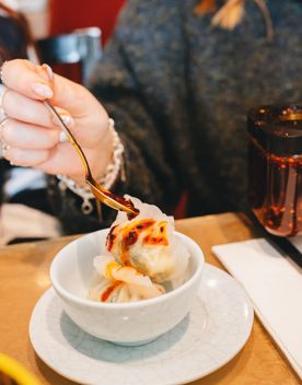 Chilli oil is poured onto a couple of dumplings in a bowl.