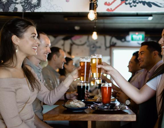 Four people sharing pints of craft beer and some appetizers at Garage Project Taproom.