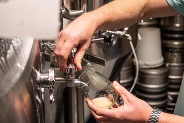 A glass of beer is being poured from a keg.