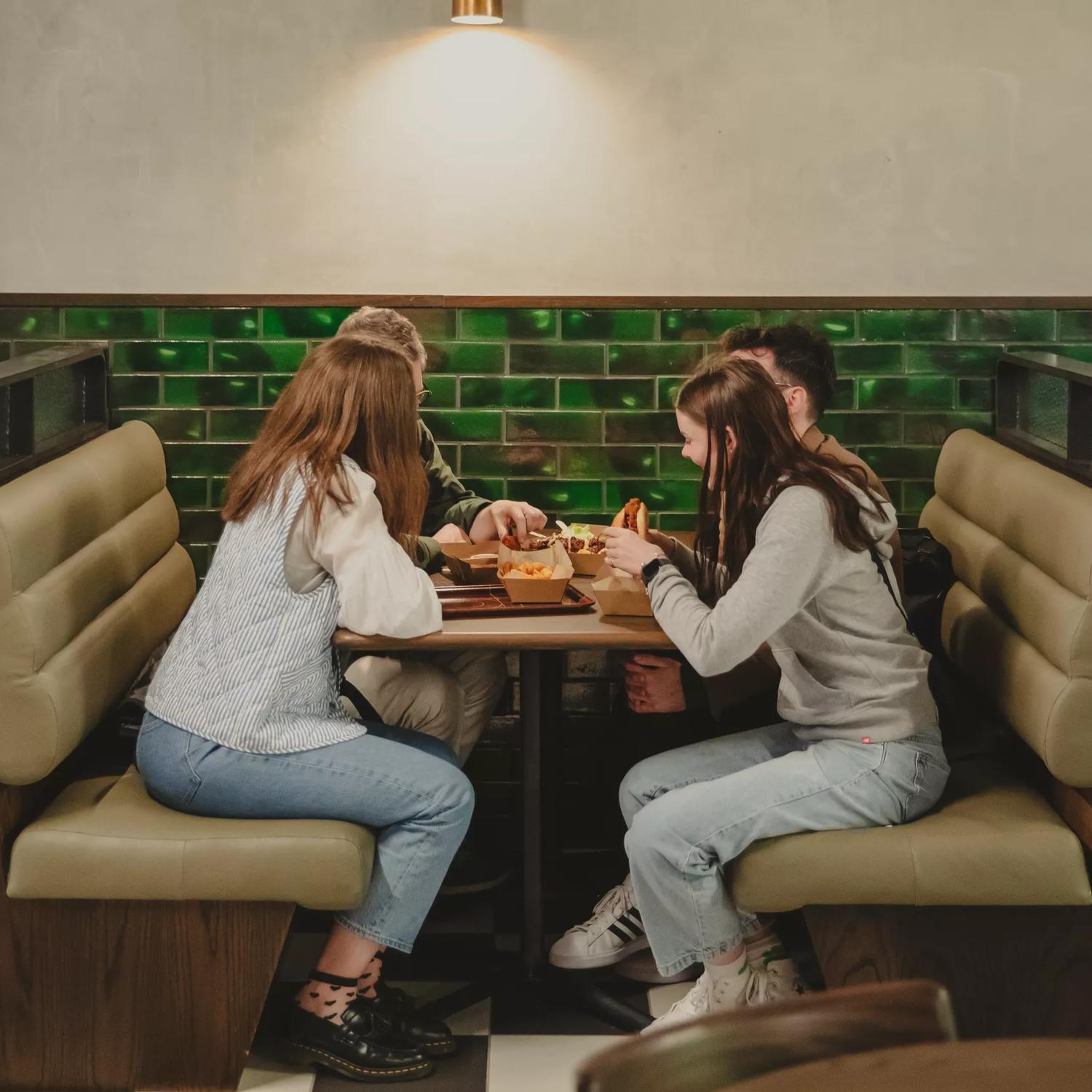 4 people eating while sat at a booth table in Willis Lane.