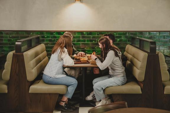 4 people eating while sat at a booth table in Willis Lane.