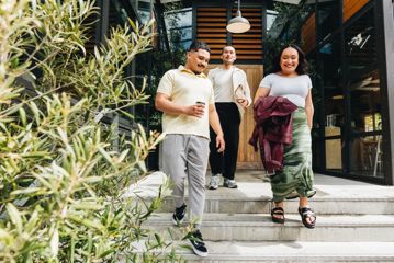 Three people walk down the steps outside Prefab.