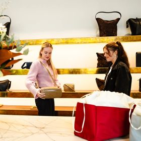 Two people browsing luxury leather handbags inside the Yu Mei Wellington store, with shelves of neatly displayed bags in a stylish, modern retail space.