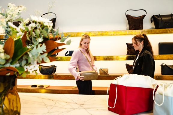 Two people browsing luxury leather handbags inside the Yu Mei Wellington store, with shelves of neatly displayed bags in a stylish, modern retail space.