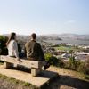 Two people sit on a bench at Rangitoto Lookout.