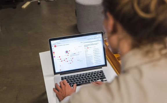 Peering over a person's shoulder to look at their laptop screen showing the Litmaps website.