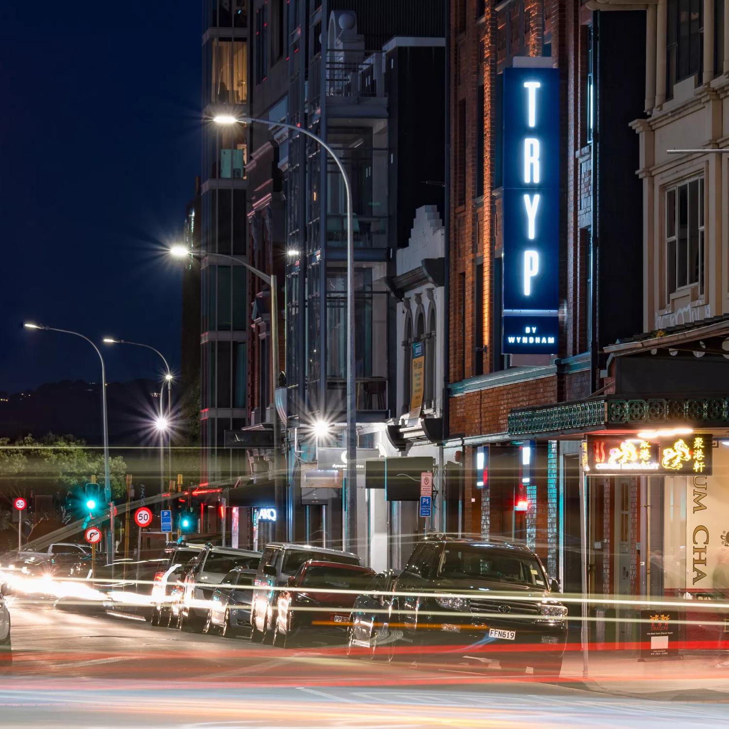 A long exposure shot of the TRYP by Wyndham Wellington exterior at night time, with car headlines creating streams of light.