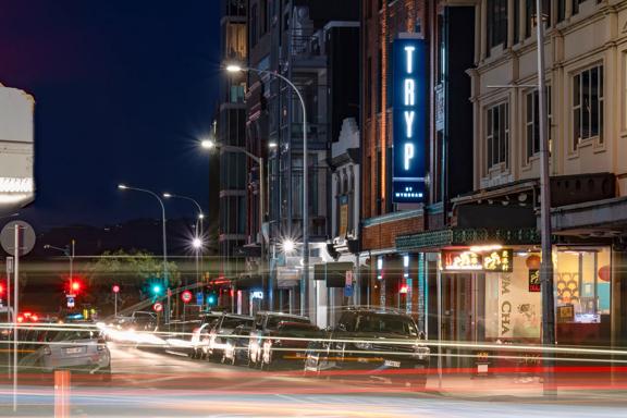 A long exposure shot of the TRYP by Wyndham Wellington exterior at night time, with car headlines creating streams of light.