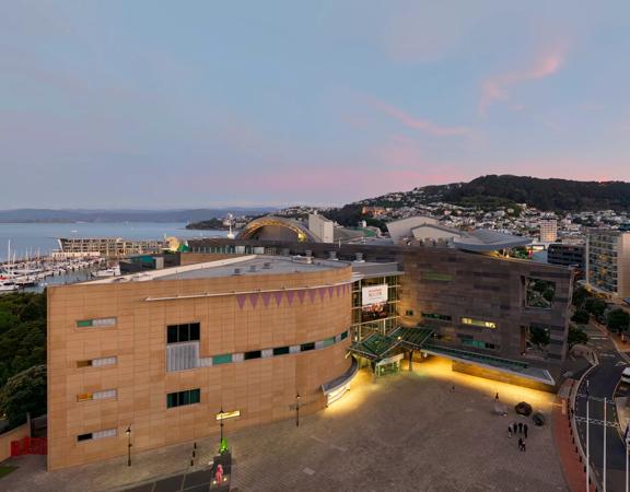 Drone image of Te Papa and Tākina at sunset, with view of Wellington harbour, Mount Victoria and city in background.