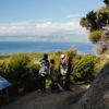 A family on the Okupe Valley Loop Track on Kapiti Island. They are standing at a viewpoint where they can see the Kāpiti Coast.