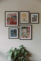 Five framed watercolour paintings on an off-white wall and a leafy green plant at Margot, a restaurant in Newtown, Wellington, New Zealand.