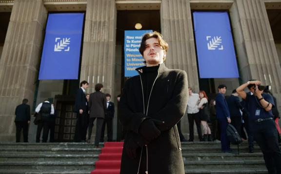 Flynn Biara Allen wears all black standing on the red carpet outside of the New Zealand Youth Film Festival.