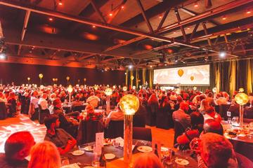 A large conference inside Lower Hutt Events Centre. Red lighting lights the room up.