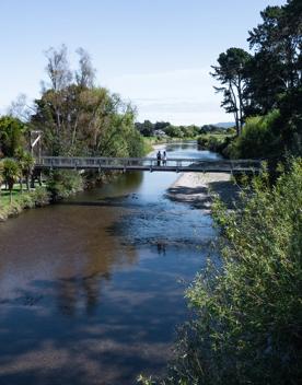 Two people are on a bridge on the Waikanae River Trail in Kāpiti Coast, New Zealand.