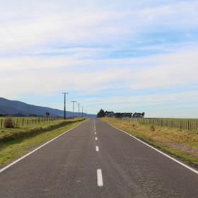 The rural Western Lake road, which connects the Remutaka Range to Lake Wairarapa, features lush green fields and mountains.