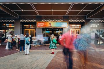 Festival attendees gather outside of St James Theatre with the Aotearoa New Zealand Arts Festival displayed on the marquee.