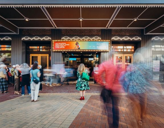 Festival attendees gather outside of St James Theatre with the Aotearoa New Zealand Arts Festival displayed on the marquee.