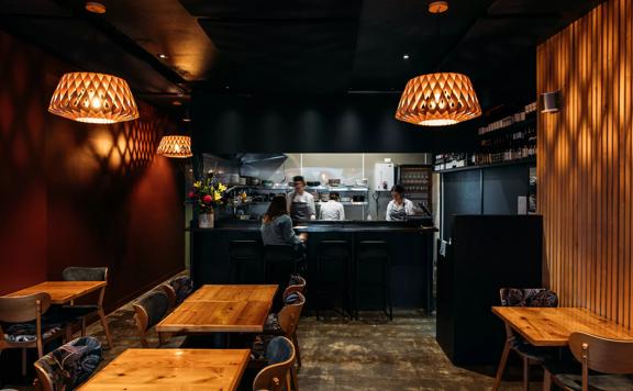 Warmly-lit interior of 50-50 restaurant, with an open kitchen in the back.