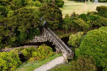 A small wooden bridge over a river on the Gums Loop trail in Wainuiomata Park.