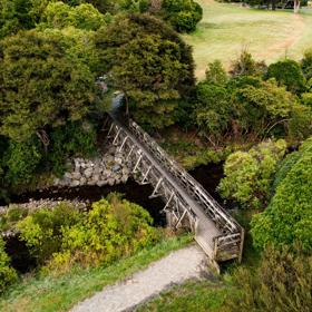 A small wooden bridge over a river on the Gums Loop trail in Wainuiomata Park.