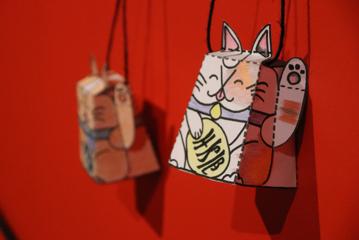 DIY cardboard maneki-neko cats hanging on a wall.