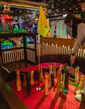 The interior of Holey Moley, the mini golf course and bar in Willis Lane, located at 1 Willis Street in Wellington. A person puts on a course with mannequin arms fixed to the felt floor reaching upward as an obstacle around the whole.