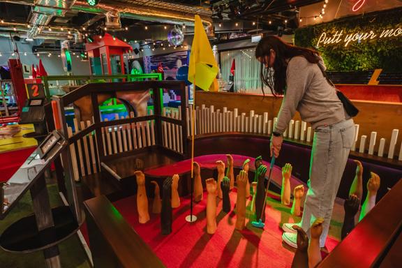 The interior of Holey Moley, the mini-golf course and bar in Willis Lane, located at 1 Willis Street in Wellington. A person puts on a course with mannequin arms fixed to the felt floor reaching upward as an obstacle around the whole. 