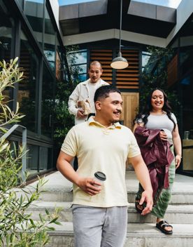 Three friends exit Wellington's Prefab eatery with takeaway coffee in hand.