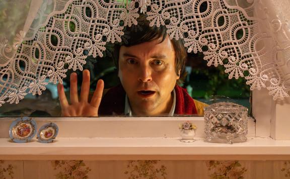 Person peeking through a window with lace curtain on the Small Town Scandal film set