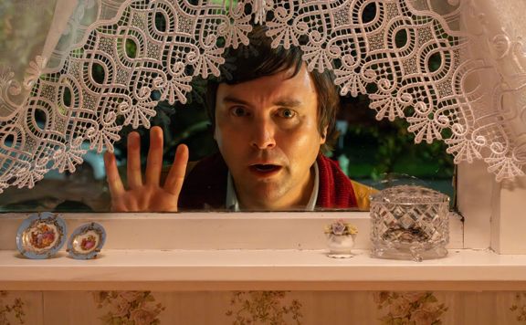 Person peeking through a window with lace curtain on the Small Town Scandal film set