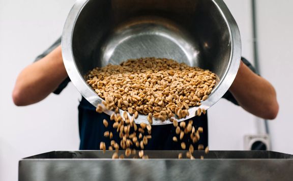 Peanuts are being poured from a large silver bowl at the Fix & Fogg factory.