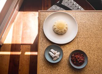Three dishes served on a wooden table inside Rita in Aro Valley.