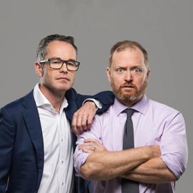 Two office workers pose in front of a grey background.