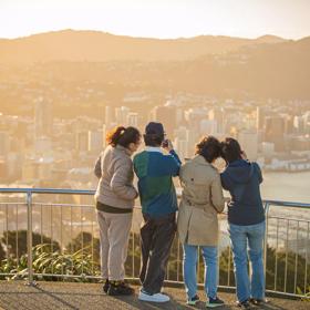 Four people are taking pictured from the look out at Mount Victoria in Wellington.