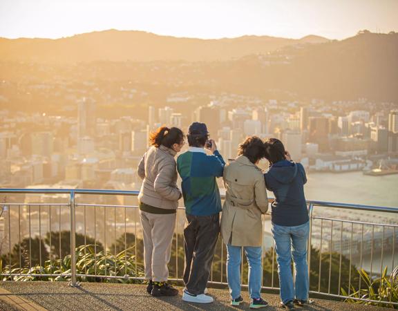 Four people are taking pictured from the look out at Mount Victoria in Wellington.