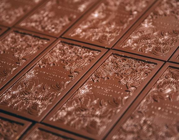 Artisanal dark chocolate bars, imprinted with a floral design, on a baking sheet at the Wellington Chocolate Factory.