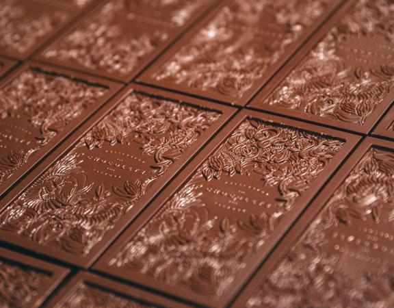 Artisanal dark chocolate bars, imprinted with a floral design, on a baking sheet at the Wellington Chocolate Factory. 