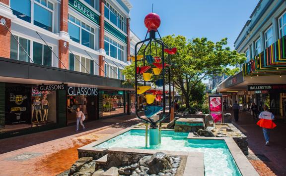 People walking down Cuba Street, past the Bucket Fountain, an iconic kinetic sculpture.