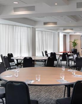 A conference room at the Rydges Hotel located at 75 Featherston Street, Pipitea in Wellington. There are five large round tables with eight chairs at each.