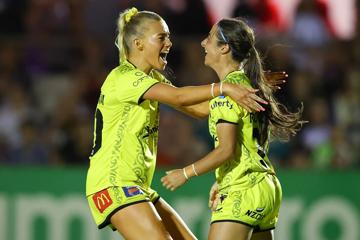 Two Wellington Phoenix FC players embrace each other to celebrate a goal.