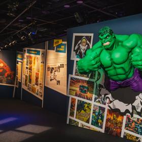 Inside the Marvel Earth's Mightiest Exhibition at Tākina, a life sized Hulk breaks out of a wall of comic books.