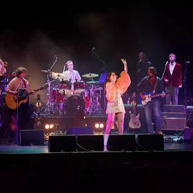 New Zealand supergroup tribute band, Come Together, is performing on stage with a full band.