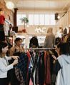 The interior of Hunters & Collectors, a vintage clothing store in Te Aro, Wellington. Three shoppers are looking through the items on a clothing rack.