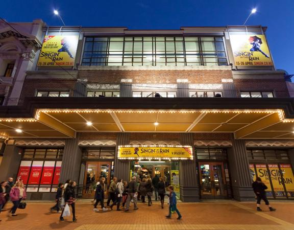 Looking up at St James theatre from the road, as people walk inside to enjoy a show.