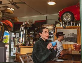 A customer sipping a coffee and looking out the window at The Big Salami Cafe in Porirua.