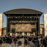 Seven musicians perform on The Park Stage at Jim Beam Homegrown, a New Zealand music festival on Wellington's waterfront to a packed audience. 